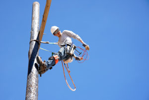 Student climbing pole at lineworker training facility